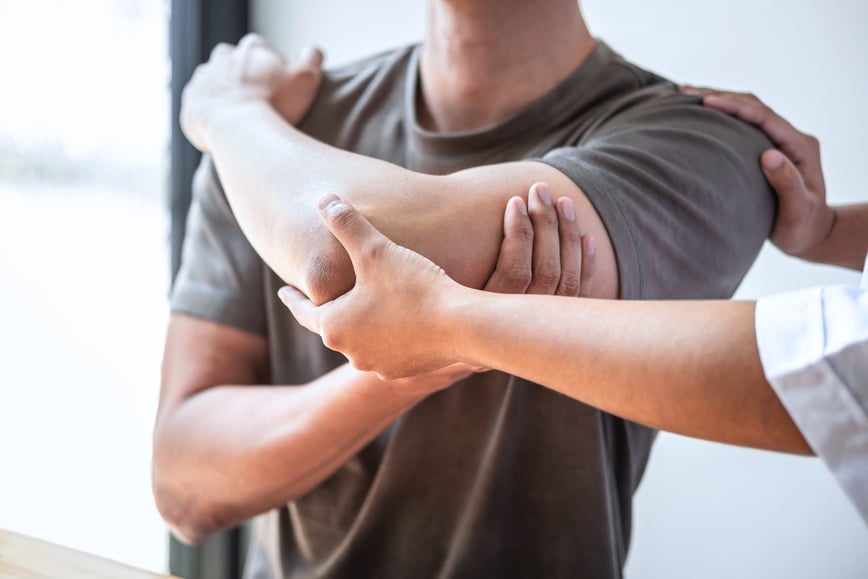 Physiotherapist Examining and Treating Injured Arm of Patient